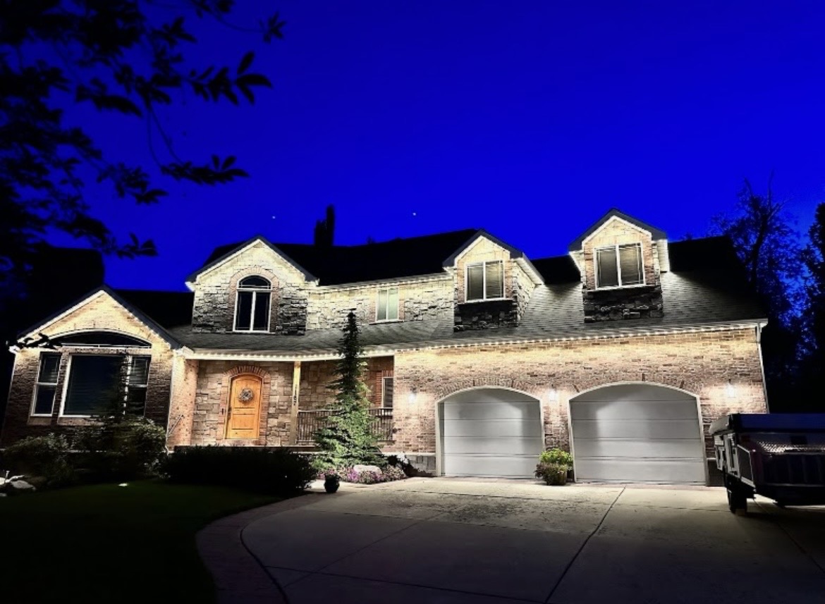 Large home illuminated by warm white permanent roofline lights