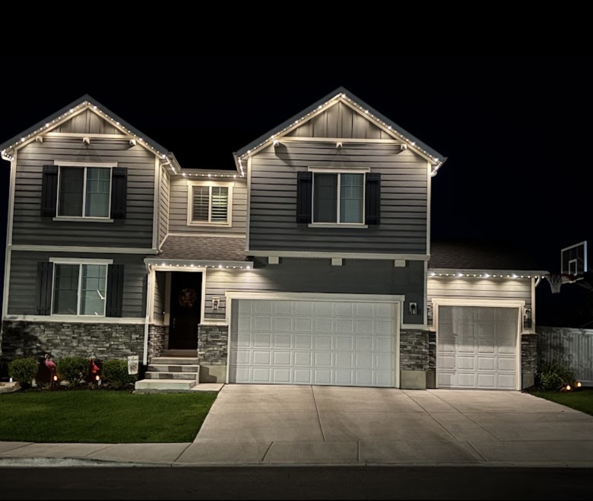 Warm white roofline lights on gray home